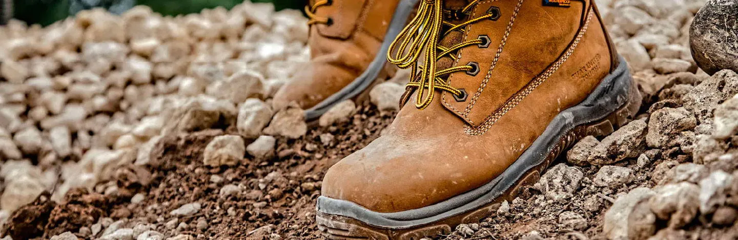 A pair of Dewalt Safety Boots shown amongst dirt and rocks