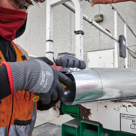 A construction worker wearing Winter milwaukee gloves cutting metal