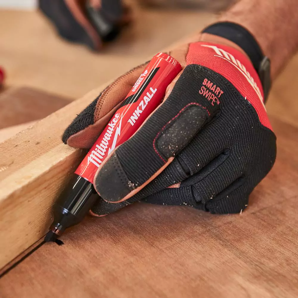 A carpenter marking a line on the floor whilst wearing milwaukee's hybrid leather gloves