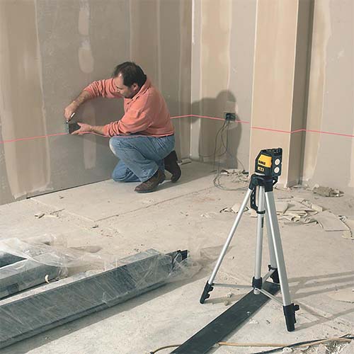 Carpenter using a dewalt dw088k red cross line laser to allign wall sockets