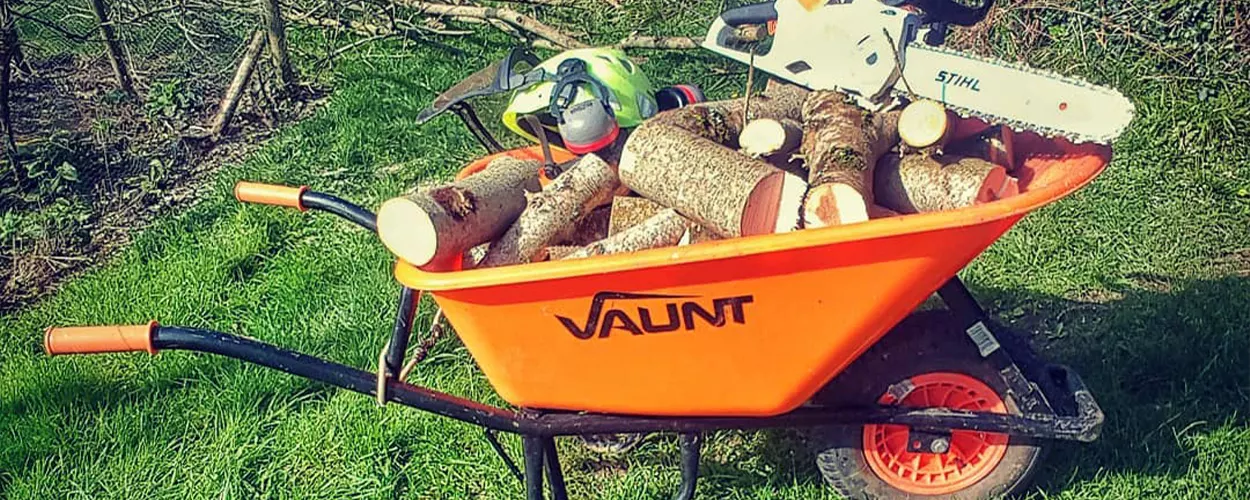 An orange vaunt wheelbarrow filled with logs