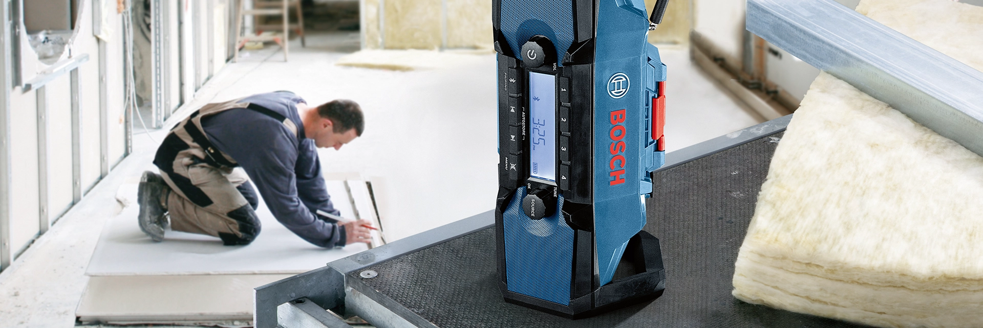 Lifestyle picture of a Tradesman working next to the Bosch GPB 18V-2 C FM Site Radio with Bluetooth.